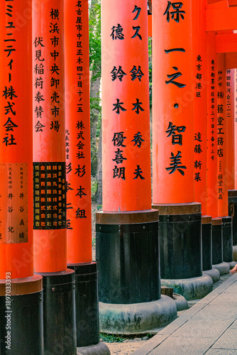 Close-up of red Torii gates with Japanese Kanji calligraphy at Fushimi Inari Shrine.