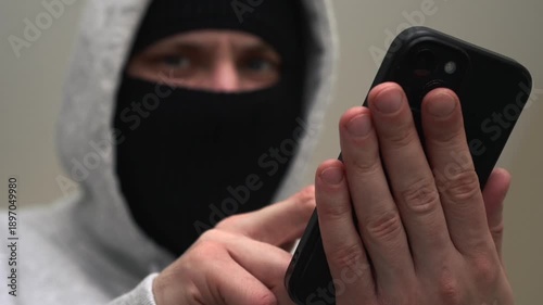 A scammer with a mobile phone in hand.
The criminal unlocks the victim's mobile phone to rob and withdraw money.