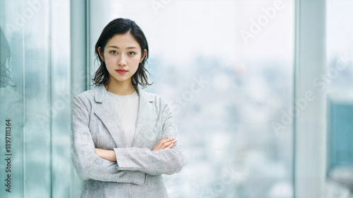 Free Download Smiling Japanese professional woman standing by a window in a high-rise office building. - GFXLoad