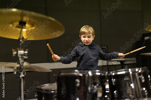 Fotografie Young boy learning playing drums in music studio