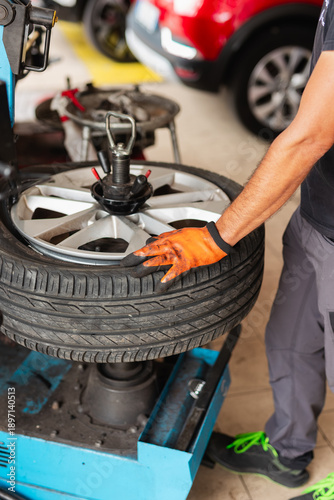 Cuadro en lienzo Mechanic in auto repair shop mounting tire on rim with tire changer