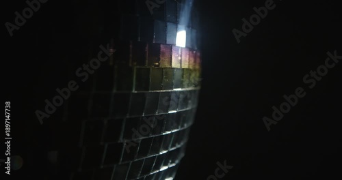A close up image capturing the shimmering reflective tiles of a disco ball, showing vibrant colors. Slow motion.
