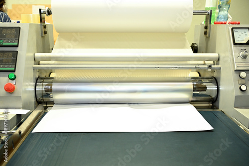 Foto Work behind the laminator in the production shop of the printing house