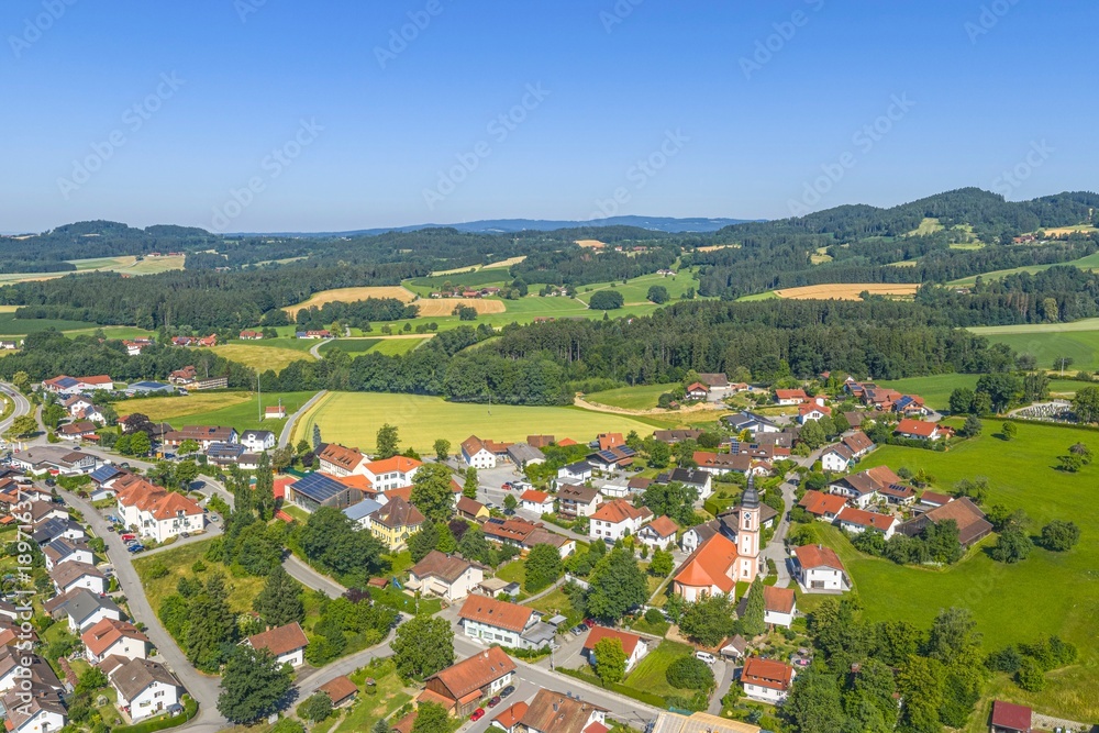 Fototapeta premium Die Gemeinde Neukirchen in der niederbayerischen Region Donau-Wald aus der Vogelperspektive