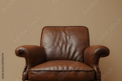 A brown leather armchair stands alone against a beige wall, captured from a front viewpoint in a calm indoor setting.