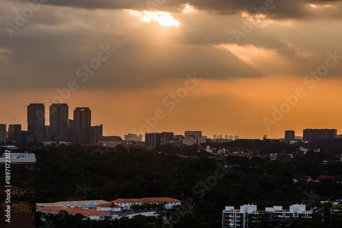 Canvas Print Dramatic sun rays piercing through dark clouds over the Kuala Lumpur city skylin