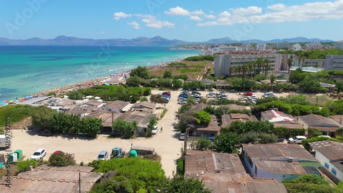 Aerial view of Playa de Muro beach in Mallorca, showcasing sandy shoreline, vibrant turquoise waters, and beachgoers enjoying the sun and surf along the coast