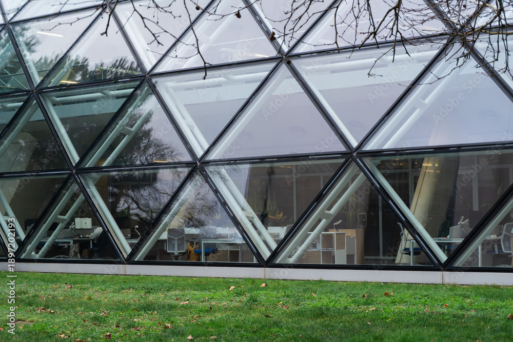 Naklejka premium Modern architecture featuring a geometric triangular glass facade and office interior