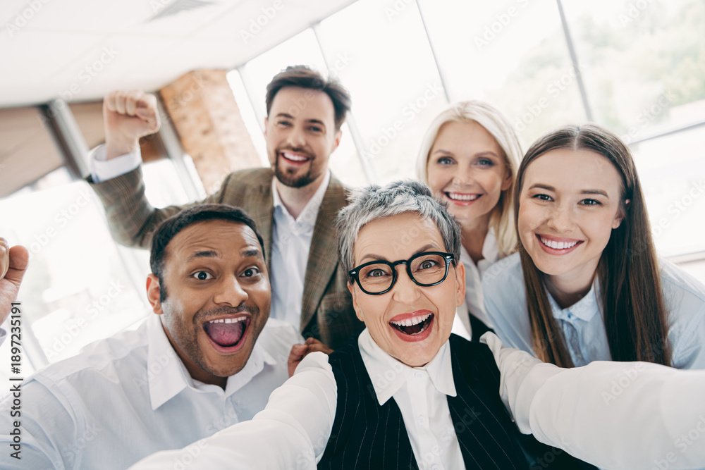 Obraz premium Group of happy business colleagues in office celebrating teamwork achievements and building strong work relationships