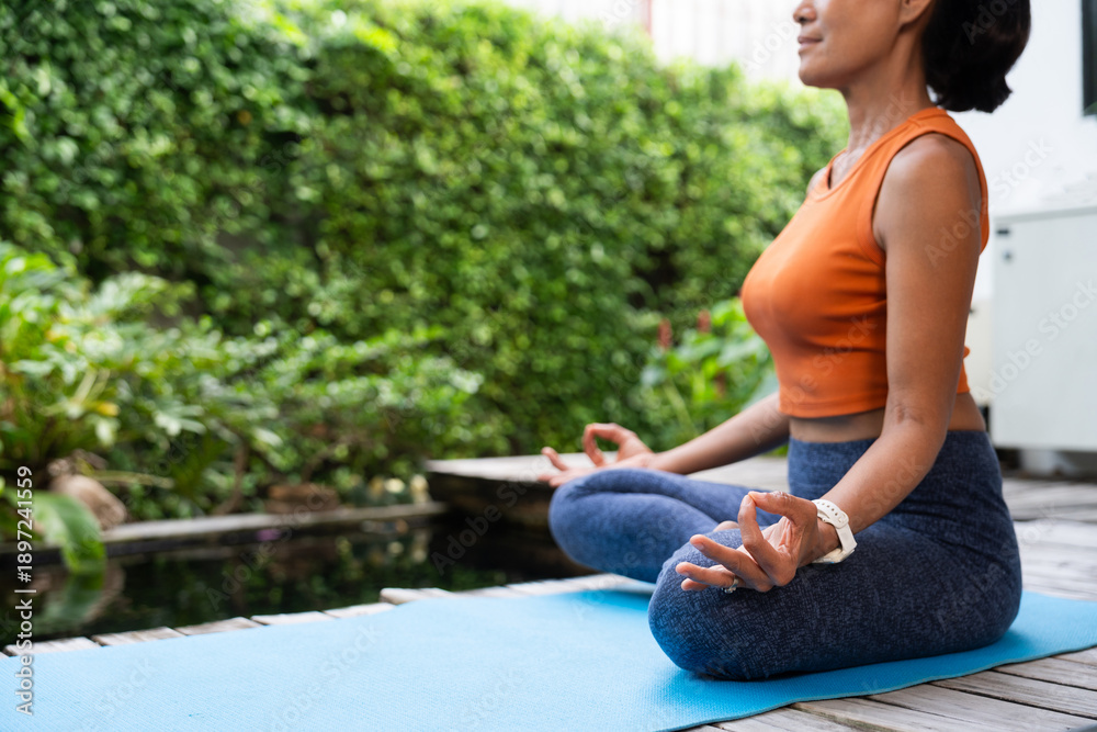 Fototapeta premium Healthy senior woman meditating outdoors on a yoga mat near nature. Practicing mindfulness and self-care, she reflects a balanced lifestyle, emotional wellness and graceful aging in a peaceful setting