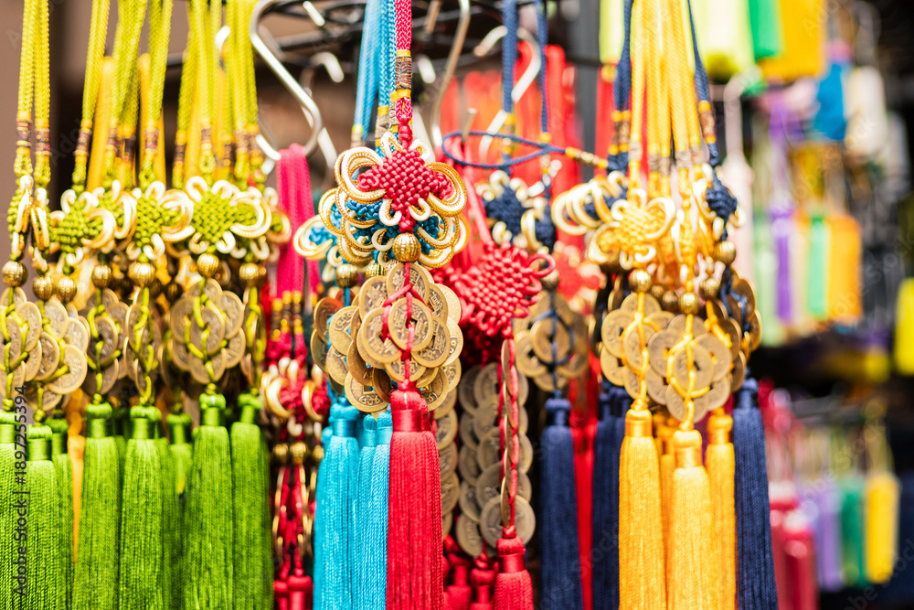 Fototapeta premium Tassels and charms are displayed on a rack at a market. They are made with different colors and materials. Shoppers can see the details in the sunlight during the day