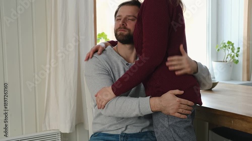 Couple comforting embrace together. Man holds woman with gentle embrace wearing casual clothes, muted living room background. Soft natural light. Tender emotional connection as they provide quiet