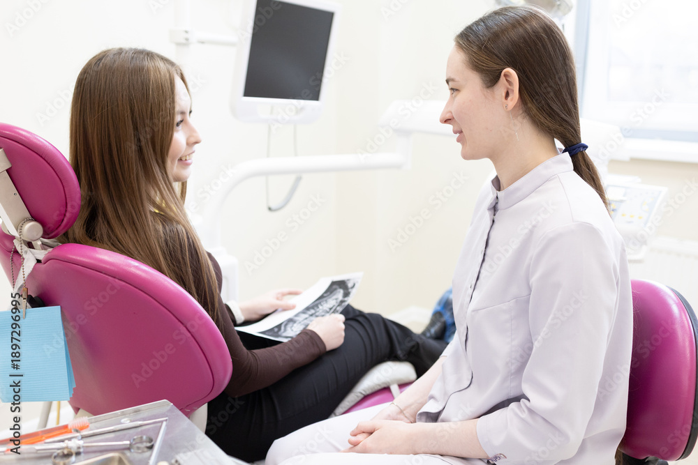 Fototapeta premium A dentist consults a patient with a dental x-ray. A dentist shows a patient an X-ray