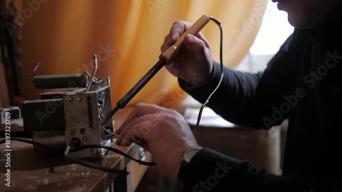 man repairing radio equipment using a soldering iron in a workshop