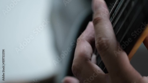 Close Up of Hand Playing Bass Guitar Strings, Person playing bass guitar with shallow depth of field, musical concept.
