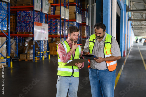 Fotografie Warehouse worker in safety uniform check the stock order details and goods supplies in the workplace warehouse