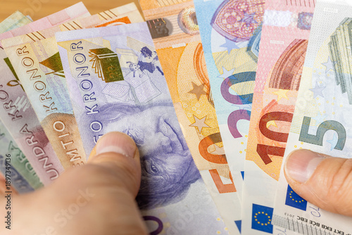 Bilde på lerret Swedish kronor in one hand and euro banknotes in the other