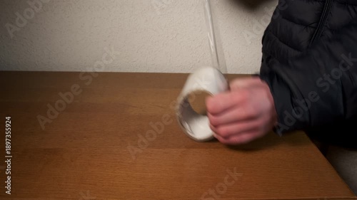 Person's hands unrolling a roll of transparent tape