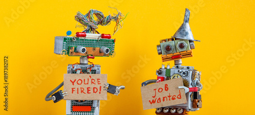 Chief robot dismisses personnel and shows cardboard sign text You are fired. Second robot is looking for a job, holds cardboard handwritten text Job wanted. Yellow background.