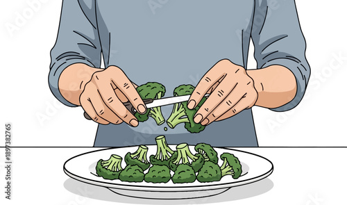 Hands using a knife to cut fresh green broccoli florets over a white plate on a table