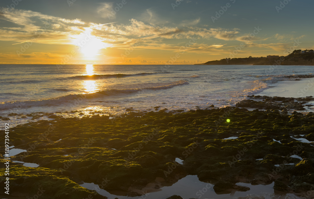 Obraz premium What a sandy beach on the Atlantic. Landscape shot at sunset of a coast with sandstone cliffs. Low tide on the yellow beach of Praia near Albufeira, Algarve, Portugal