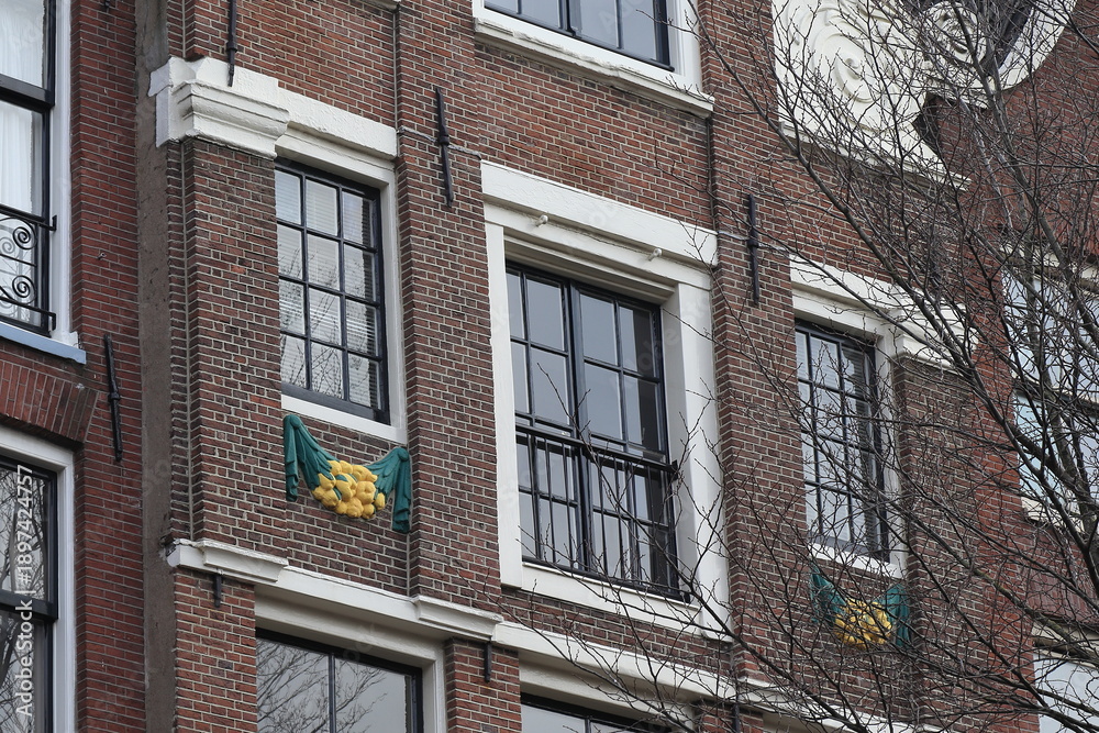 Fototapeta premium Keizersgracht Canal House Facade Close Up with Sculpted Green and Yellow Decoration in Amsterdam, Netherlands