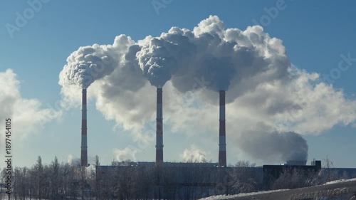 General view of the thermal power plant in winter. Thermal power plant with smokestacks releasing smoke and steam.  Timelapse, accelerated shooting.