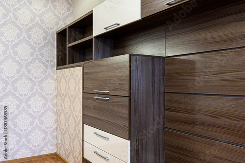 Photos Dark wood-finish wall unit with cream drawers and open shelves; paired with light patterned wallpaper, featuring sleek metal handles