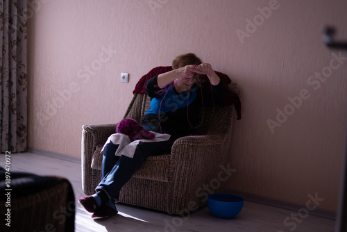 Elderly woman knitting in a chair