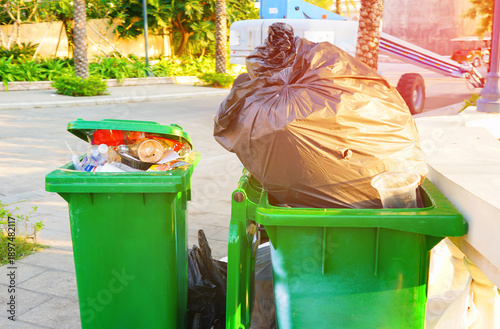Foto Trash bins with garbage in public at palm trees in cityRecycling Bin With Plastic, Full Waste