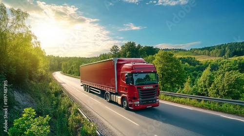 A large red freight truck traveling through a scenic eco-friendly corridor, lush greenery and blue sky, modern transport stock image