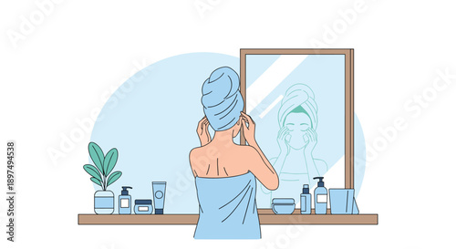 Woman standing in her bathroom looking into the mirror with a towel on her head surrounded by beauty products.