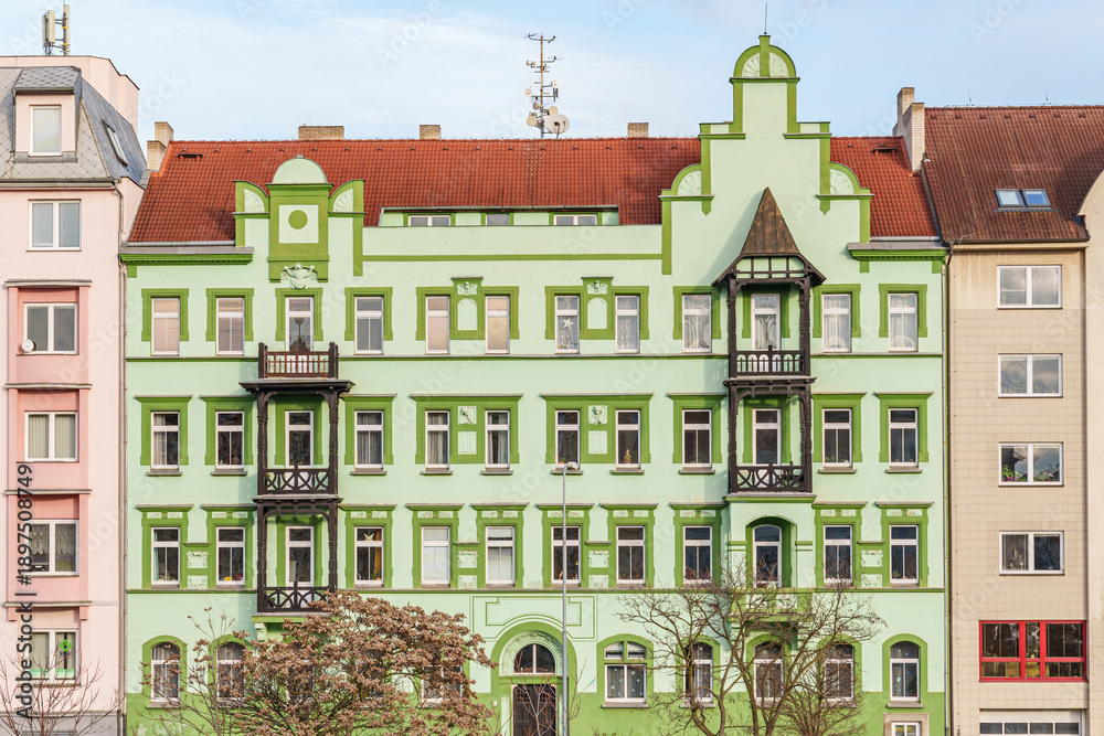 Obraz premium A green building with a red roof and a balcony in Pilsen Czech Republic. The building is tall and has many windows