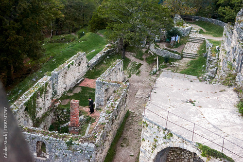 Tableau sur toile Elderly Orthodox priest walks through ruined temple, his faith persisting amid architectural decay and history