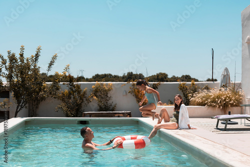 Fotografi Family enjoying summer vacation playing in swimming pool