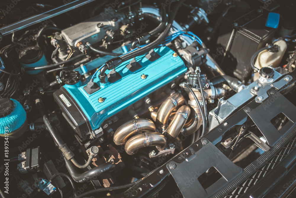 Fototapeta premium Close-up of a car engine with a custom blue valve cover and headers