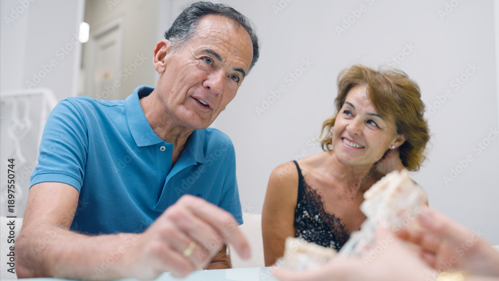 Fototapeta premium Senior man and woman discussing dental treatment options with a healthcare professional, receiving information about oral health