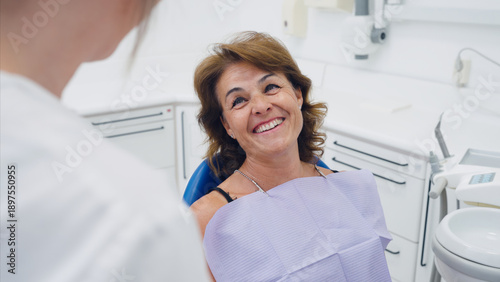 Bild auf Leinwand Mature woman patient smiling happily, looking up at the dental professional duri