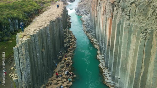 A scenic view of Studlagil Canyon in Iceland with basalt columns and a river.