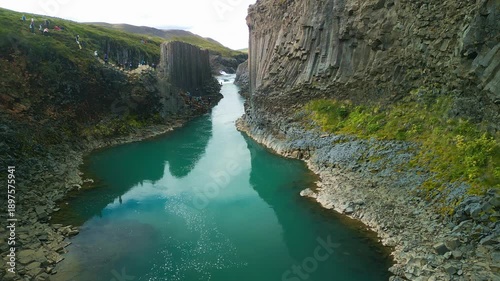 A scenic view of Studlagil Canyon in Iceland with basalt columns and a river.