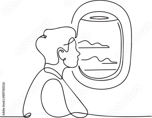 A young man gazing out of an airplane window at the landscape below during flight