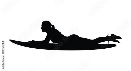 A woman lying on a surfboard viewed in profile silhouette
