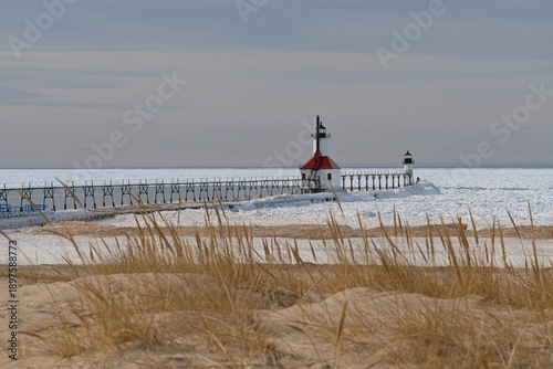 Winter lighthouse and pier on frozen Lake Michigan shoreline