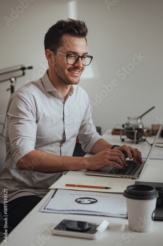 Man Working on Laptop at Desk With Coffee in Modern Office Space During Daytime