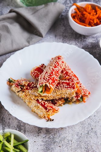 Photography Roasted crab rolls with cucumber and carrots in sesame seeds on a plate vertical