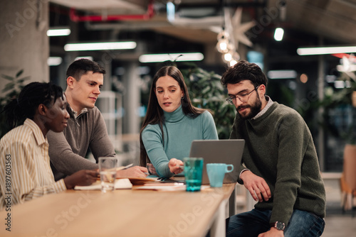 Diverse colleagues collaborating on laptop in modern office