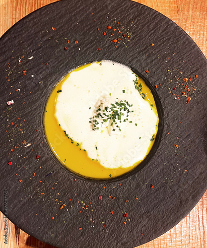 Butternut squash soup in black bowl with seasonings. 