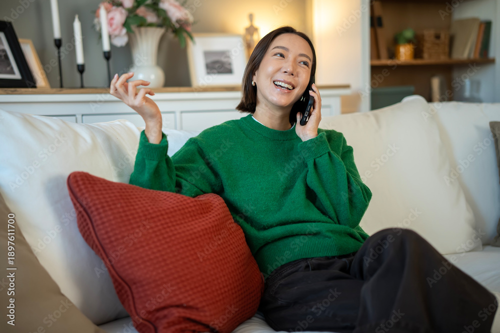 Obraz premium Woman smiling and talking on smartphone at home