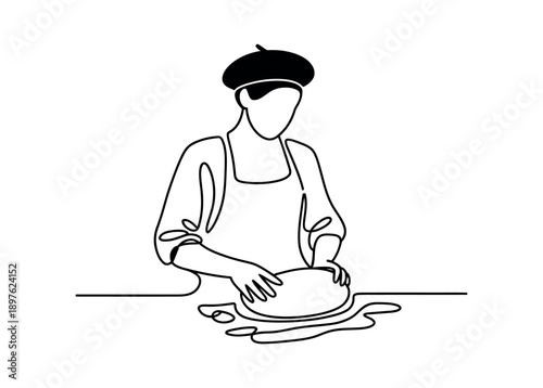 A chef in a black beret and apron preparing a meal in a minimalist kitchen