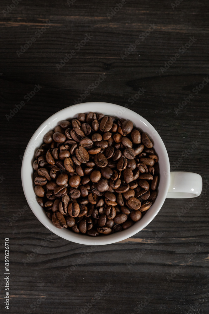 Fototapeta premium White coffee cup filled with coffee beans, minimal still life, clean background, coffee concept.